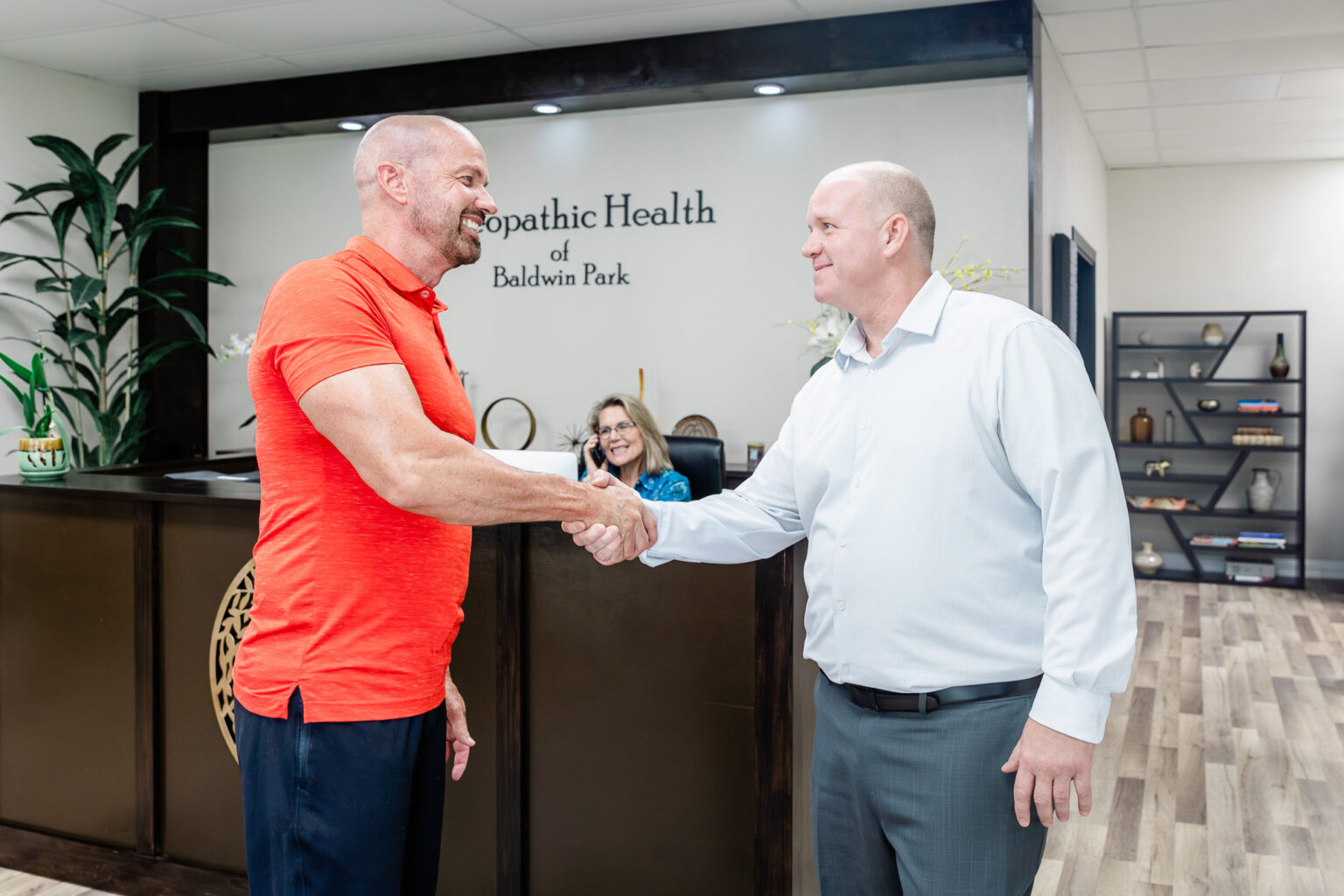 Physician welcoming a patient with a handshake at the reception desk of Osteopathic Health of Orlando