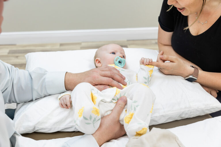 Osteopathic physician gently treating an infant with a parent nearby